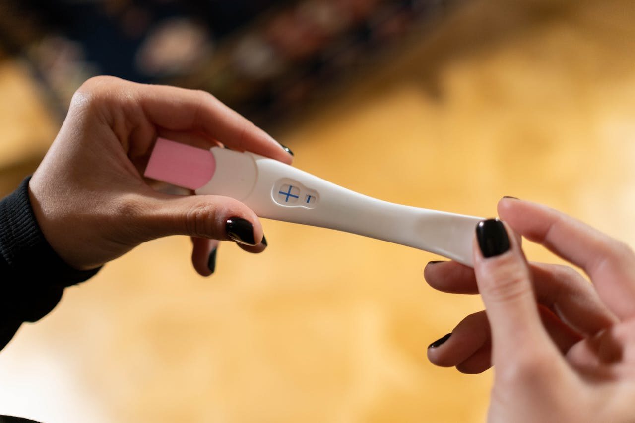 une femme tient entre ses mains un test de grossesse positif