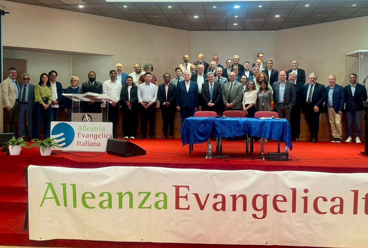 Un groupe de personnes réunies sur une scène avec une banderole "Alleanza evangelica italiana"