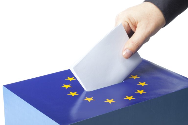 Une main d'homme dépose un vote dans une urne avec le drapeau étoilé de l'Union européenne