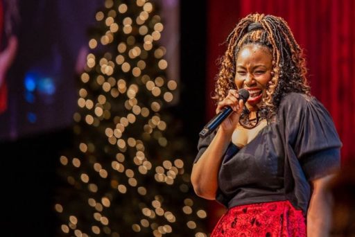 Mandisa micro à la main en train de chanter lors d'un spectacle de Noël. Un sapin lumineux est au second plan de la scène