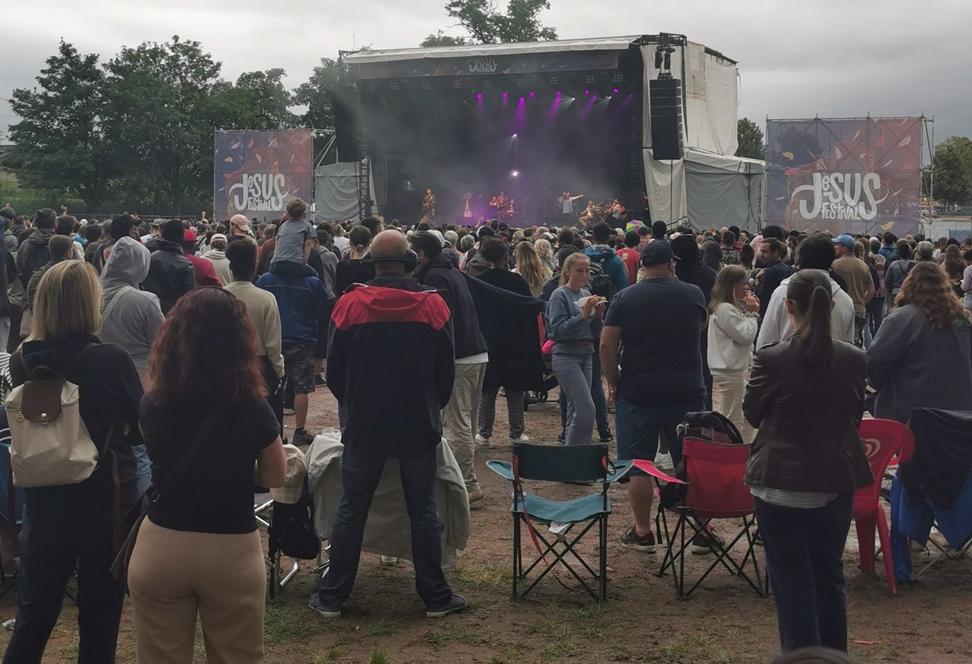 Des festivaliers debout regardent vers la scène principale du Jesus Festival