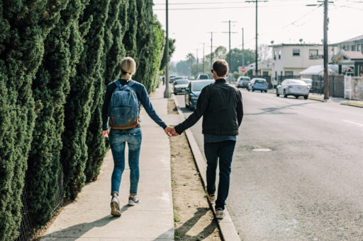 un couple de jeunes amoureux se tenant par la main marche dans la rue