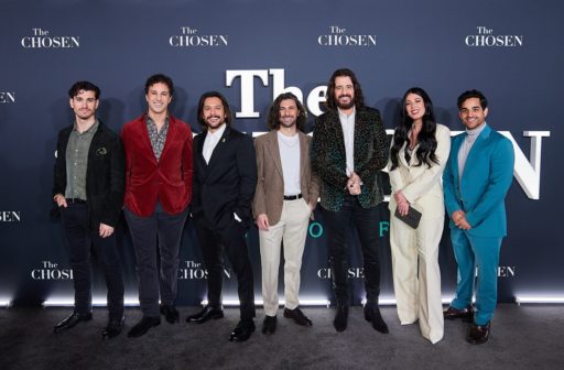 Les acteurs de la série The Chosen prennent la pose devant un roll-up avec l'inscription The Chosen